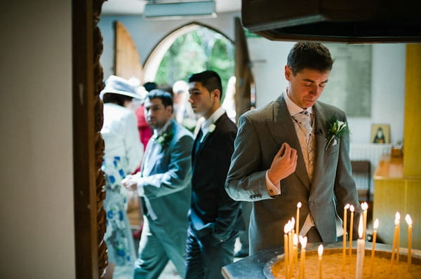 Groom looking down at candles - Picture by Kristian Leven Photography