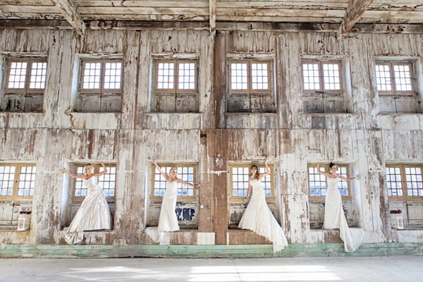 Four brides standing in windows of warehouse