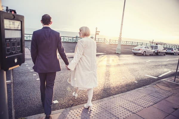 Bride and groom holding hands to cross road