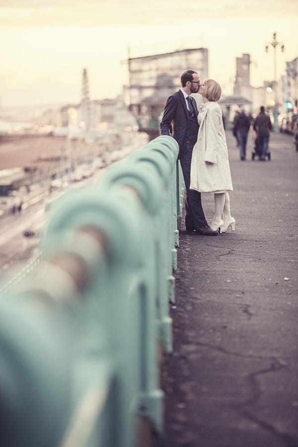 Bride and groom kissing by railings