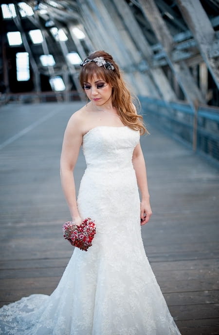 Bride looking down holding red brooch bouquet