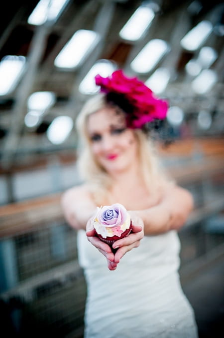 Bride holding out cupcake to camera