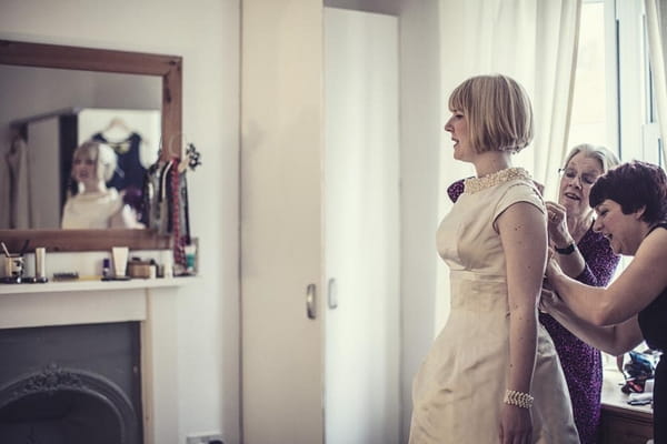 Bride looking in mirror as dress is adjusted