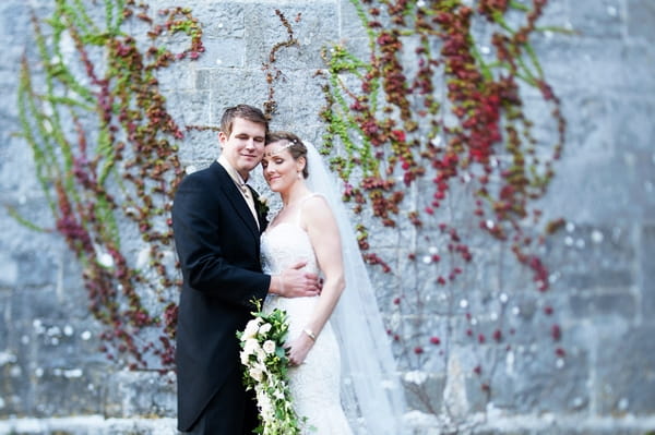 Bride and groom standing in front of wall