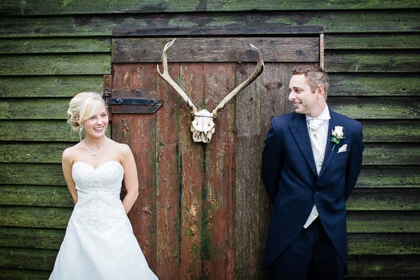 Bride and groom standing by animal skull on door