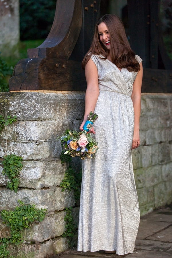 Bride standing next to wall holding bouquet