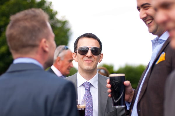 Groom wearing sunglasses drinking Guinness