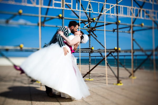 Bride and groom kiss in front of scaffolding