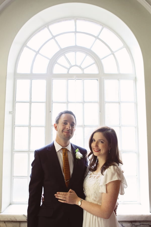Bride and groom in front of large window