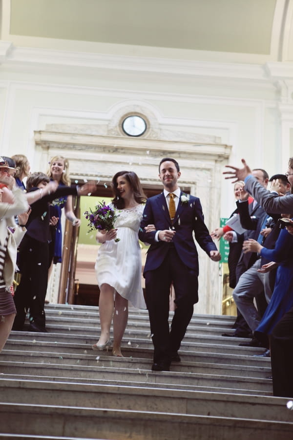 Guests throw confetti over bride and groom