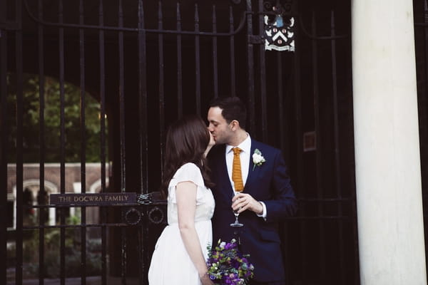 Bride and groom kiss in front of gate