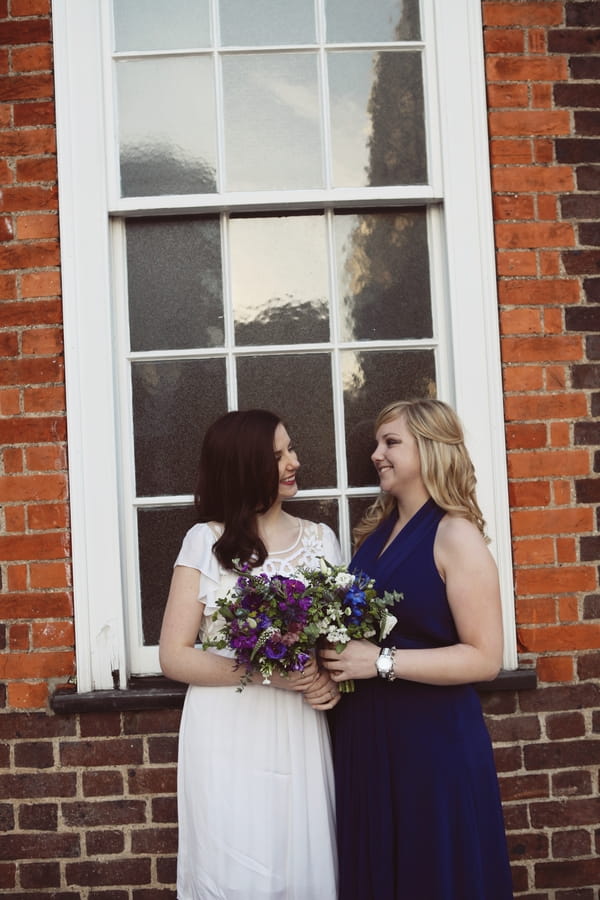 Bride and bridesmaid in front of window
