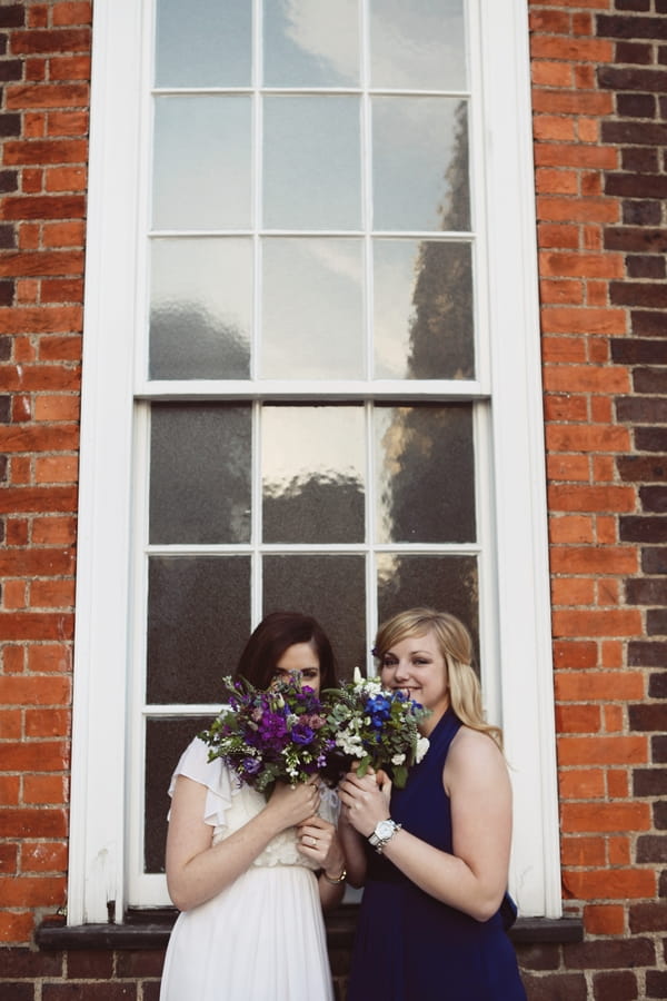 Bride and bridesmaid hide behind bouquets