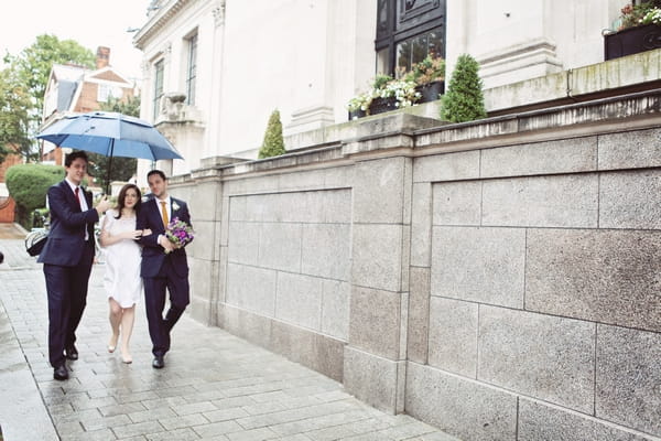 Bride and groom walking under umbrella