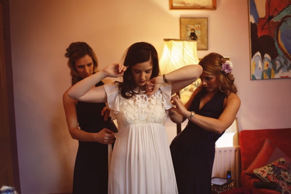 Bridesmaids helping bride with wedding dress