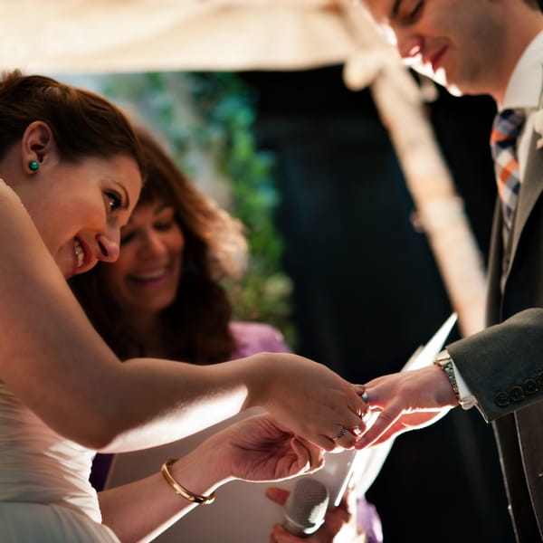 Bride placing ring on groom's finger