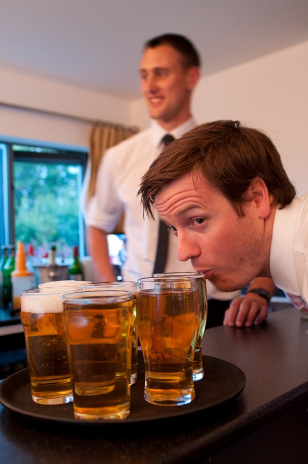 Man bending down to drink beer