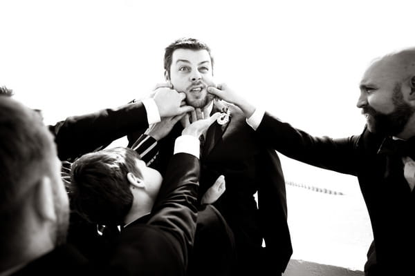 Groomsmen pulling man's cheeks