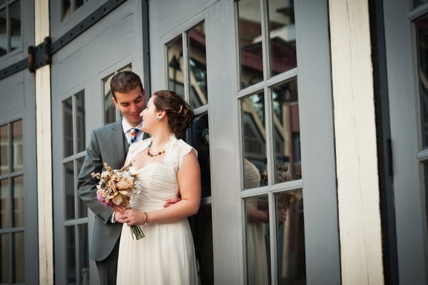 Bride and groom leaning back on door