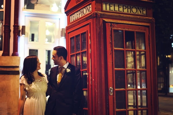 Bride and groom next to red telephone box