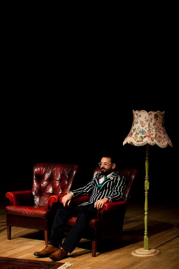 Groom sitting in leather chair waiting for bride