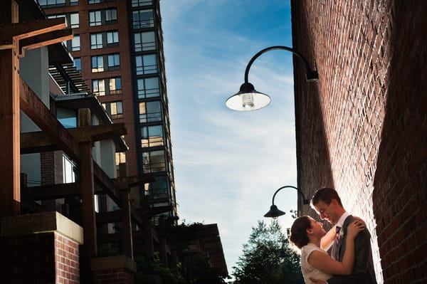 Bride and groom standing by wall under street light