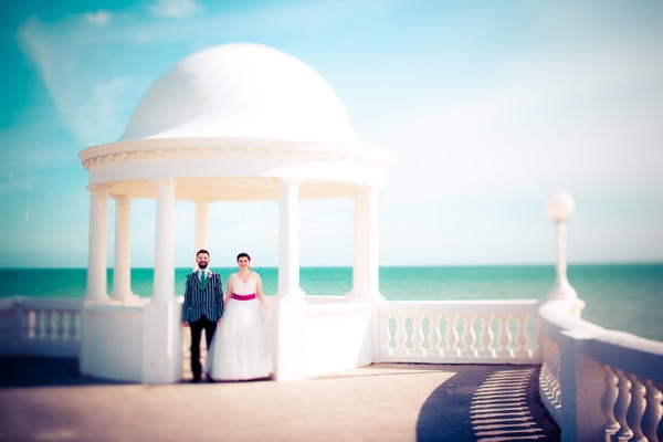 Bride and groom standing under sea-front gazebo