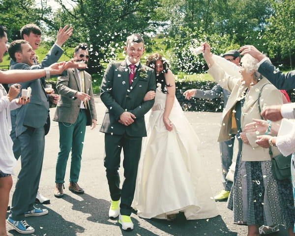 Bride and groom being showered in confetti