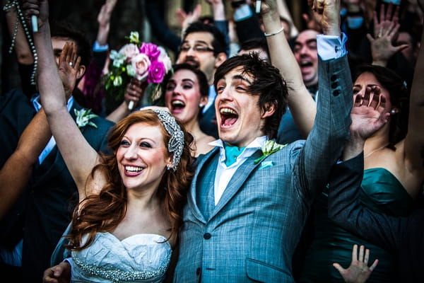 Bride and groom cheering with wedding party