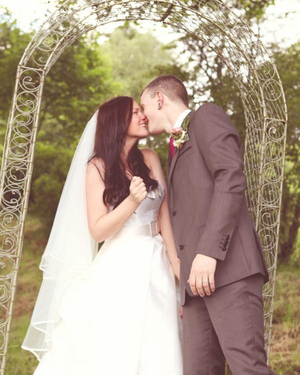 Bride and groom kiss in garden