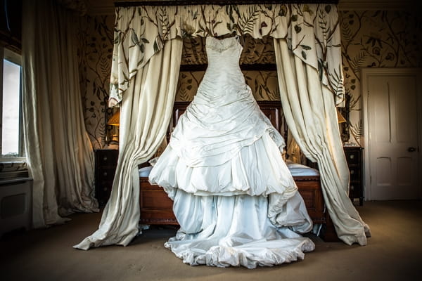 Wedding dress hanging from four poster bed