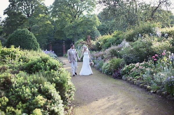 Bride and groom walking though Kirknewton Stables' gardens