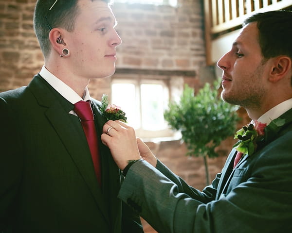 Best man adjusting groom's buttonhole