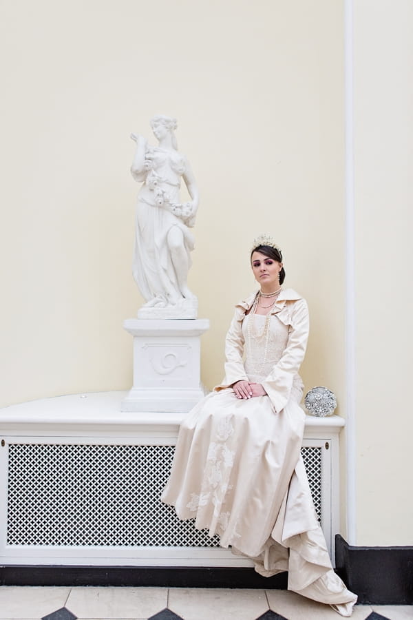 Bride sitting next to statue