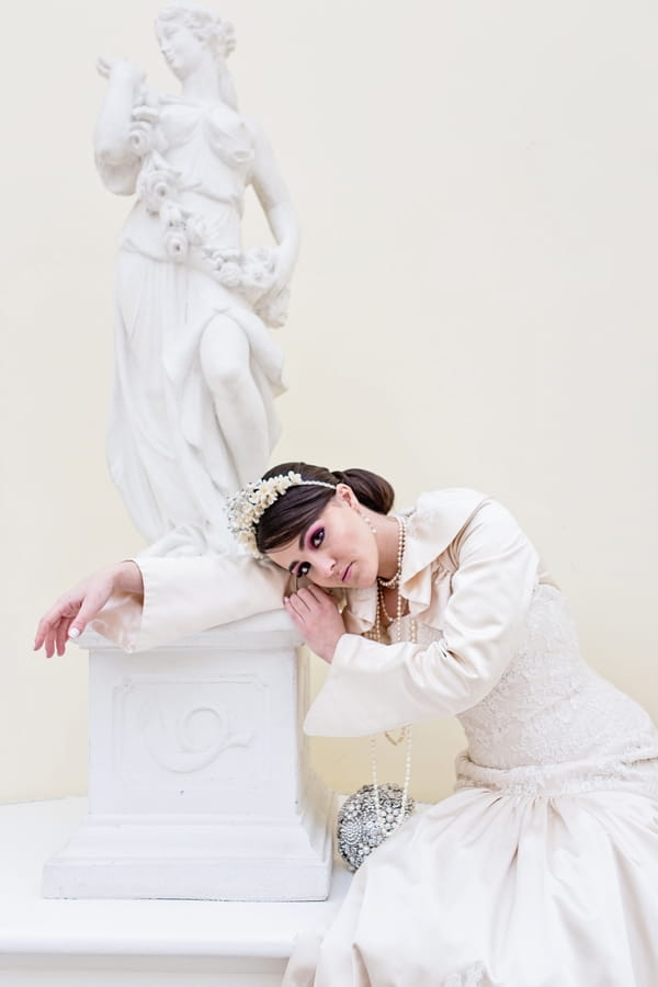 Bride leaning on statue