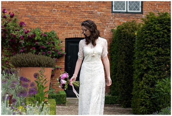 Bride looking at flowers in garden