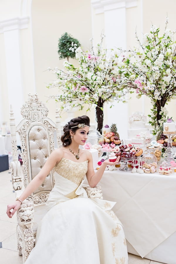 Bride sitting next to wedding cake table