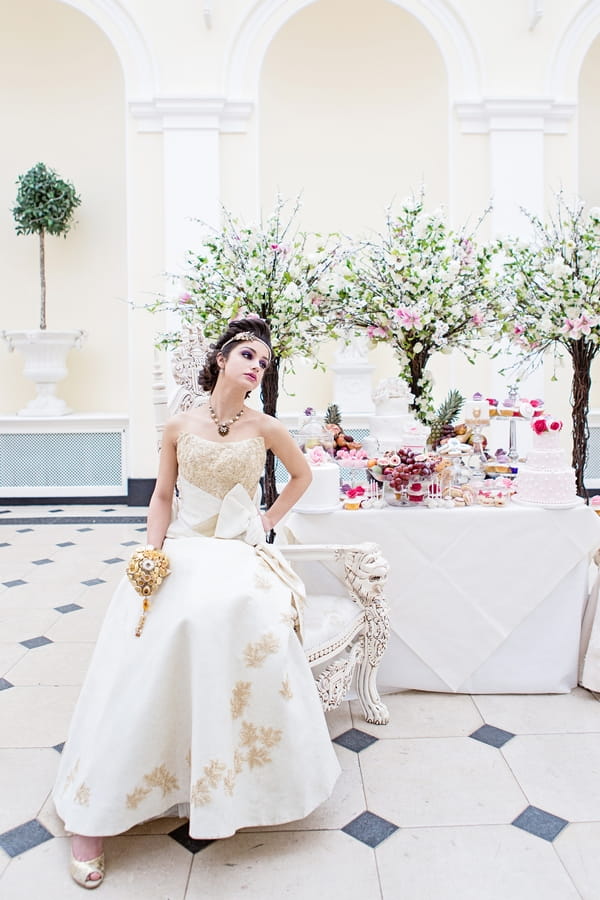 Bride sitting next to cake table