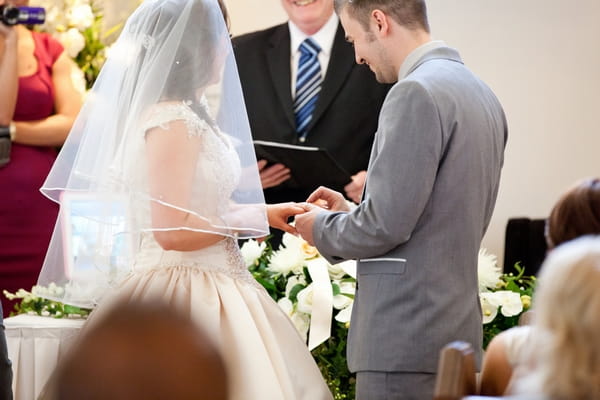 Groom placing ring on bride's finger