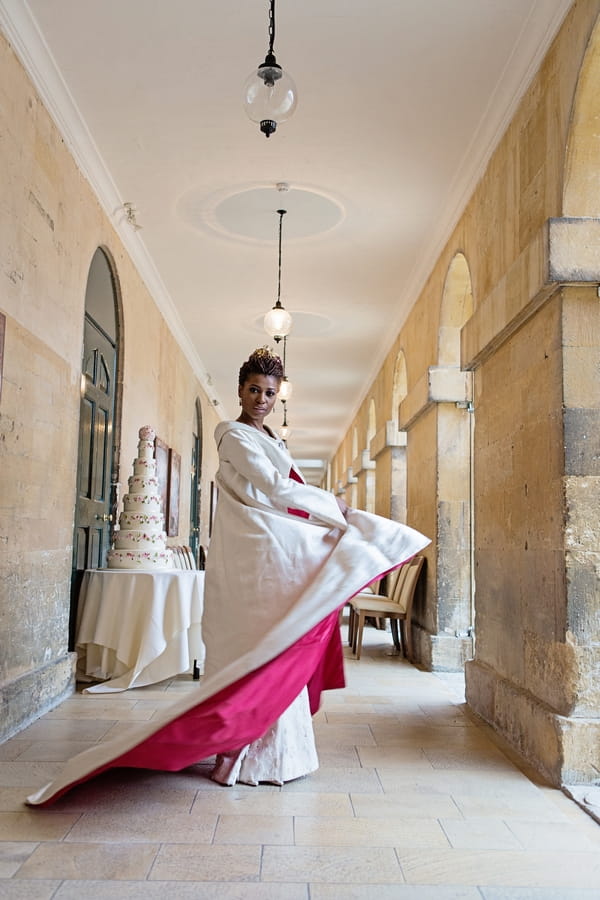 Bride twirling in red-lined long wedding coat