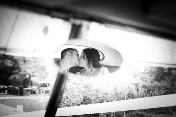 Bride and groom in mirror of wedding car