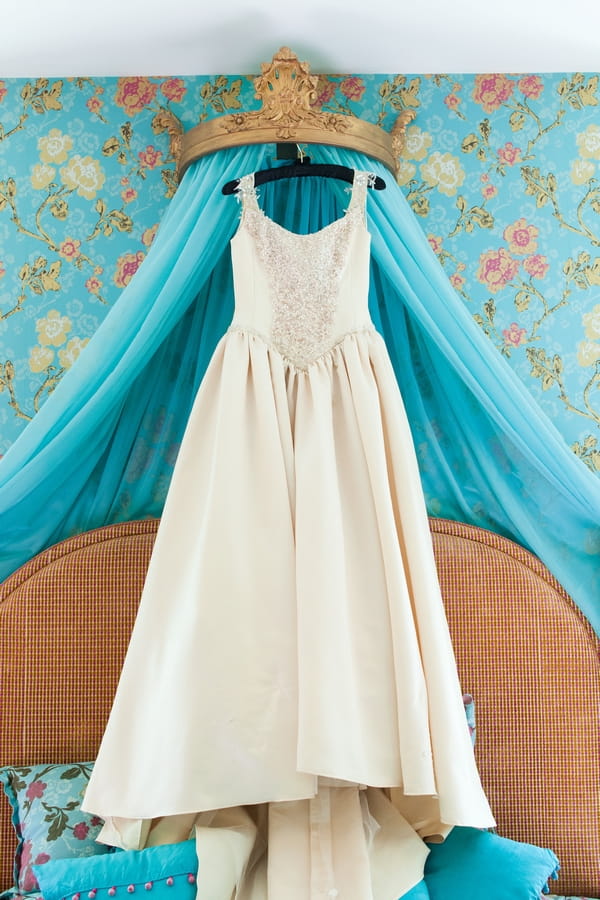 Wedding dress hanging on end of bed