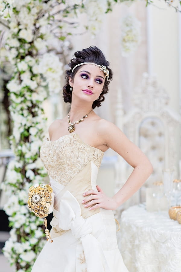 Bride holding gold brooch bouquet