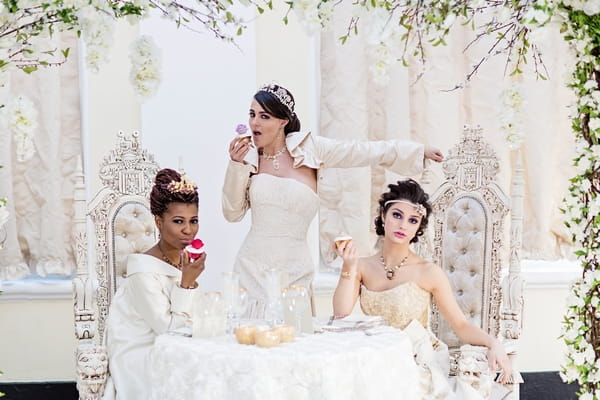 Brides sitting at table with cakes