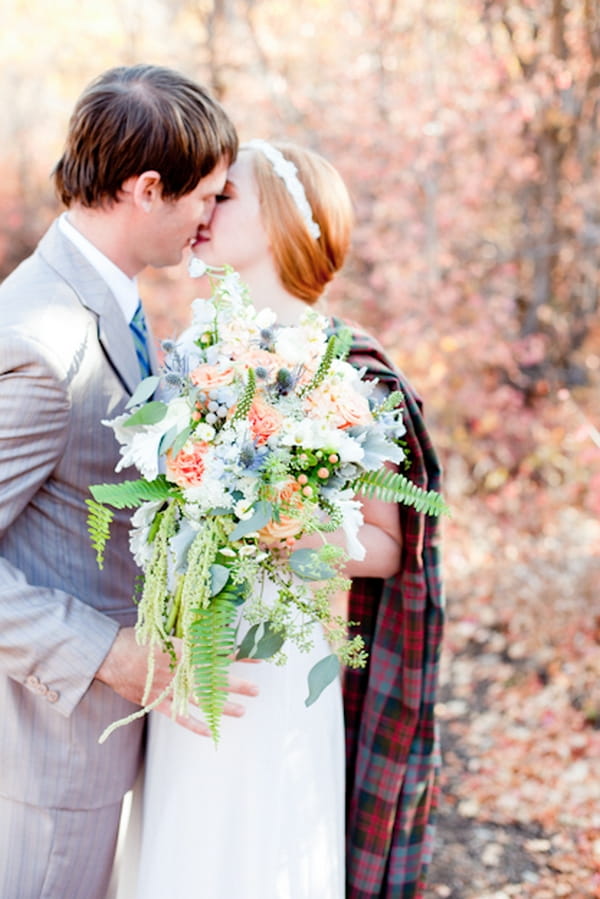 Bride and groom kiss in front of bouquet