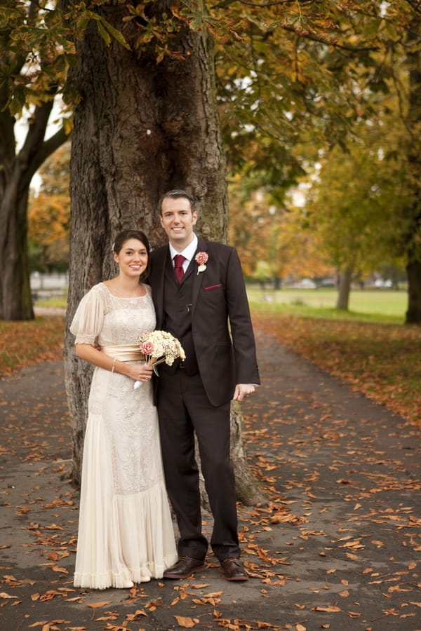 Bride and groom standing by tree