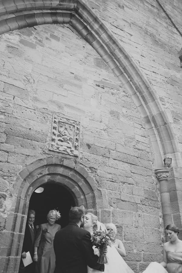 Bride and groom kiss outside church