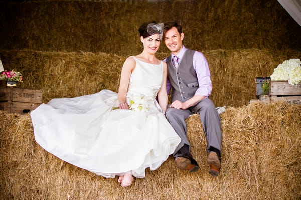 Vintage bride and groom sitting on hay bales