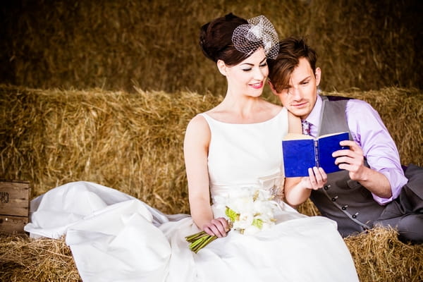 Bride and groom on hay bales reading a book