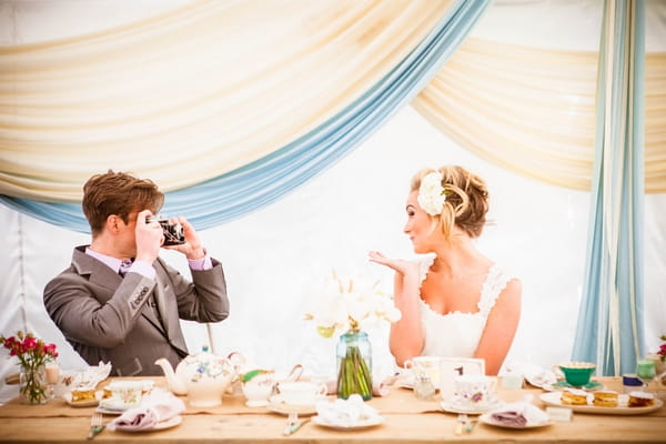 Bride blowing kiss as groom takes picture